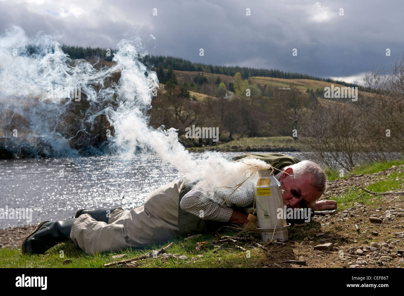 Salmon fisherman using a Kelly's Kettle, River Oykel, Sutherland, Scotland, UK Stock Photo