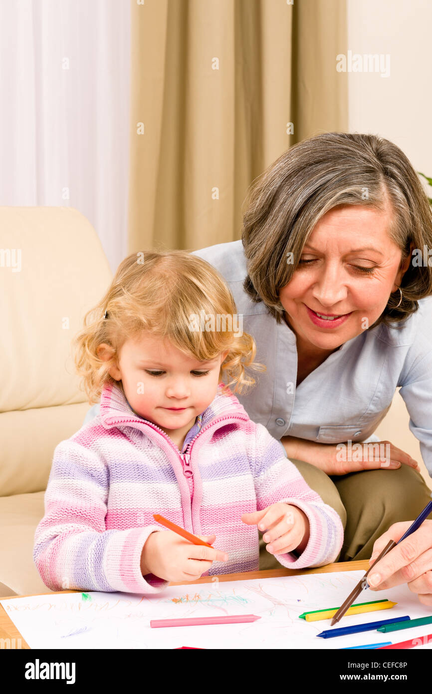 Grandmother and granddaughter drawing together with pencils at home