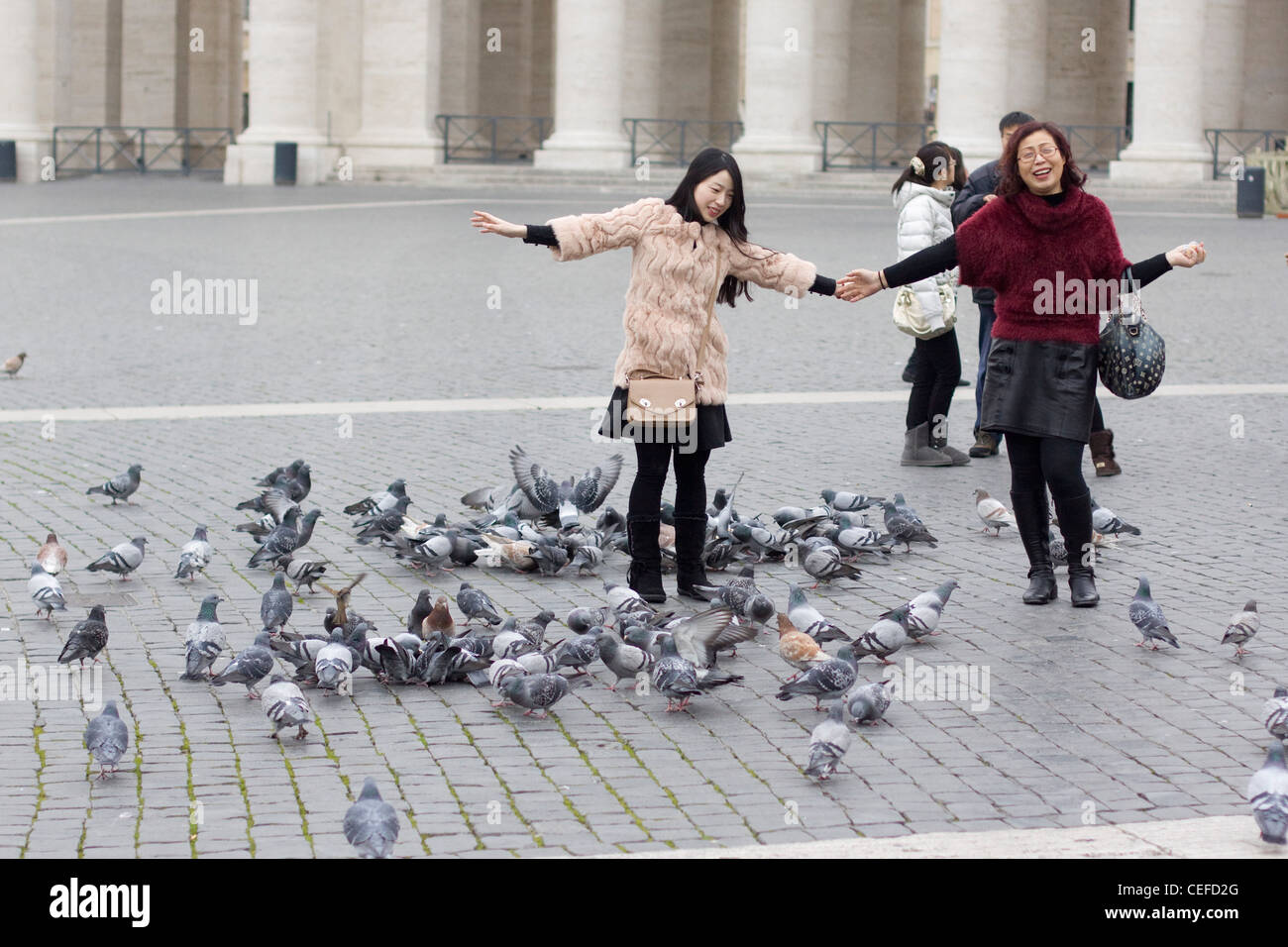 Two Chinese Ladies posing with the Pigeons in the St. Peter's Basilica Basilica di San Pietro Vatican city Rome Stock Photo