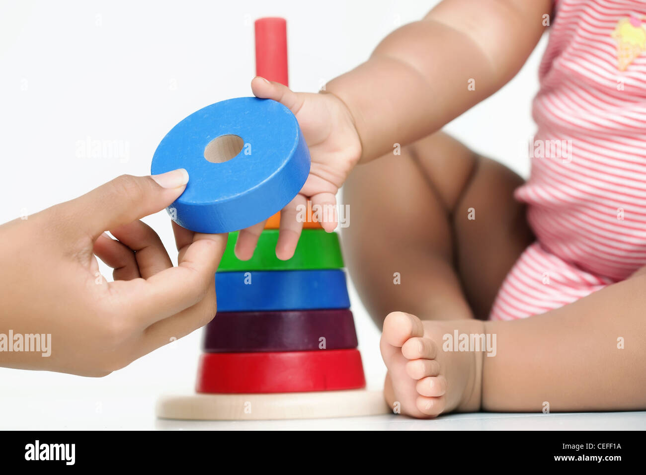 A building block being handed by an adult hand to a baby who is sitting ...