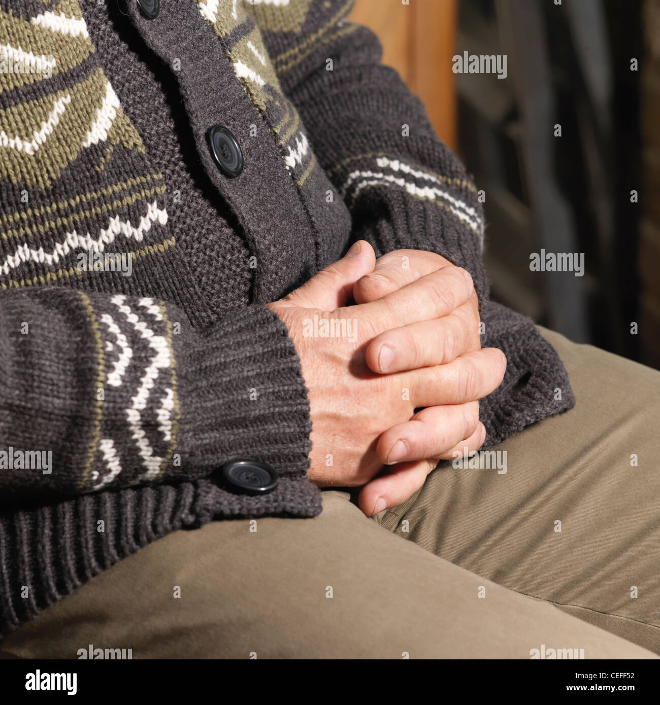 Older man sitting with hands folded Stock Photo