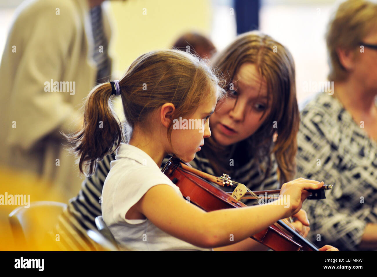 A music teacher gives violin lessons to 7 year old girl in a primary school Stock Photo