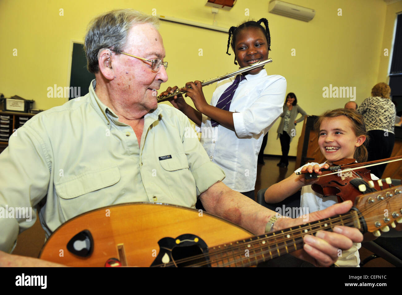 Intergenerational orchestra, young and old play music together in a Primary School UK Stock Photo