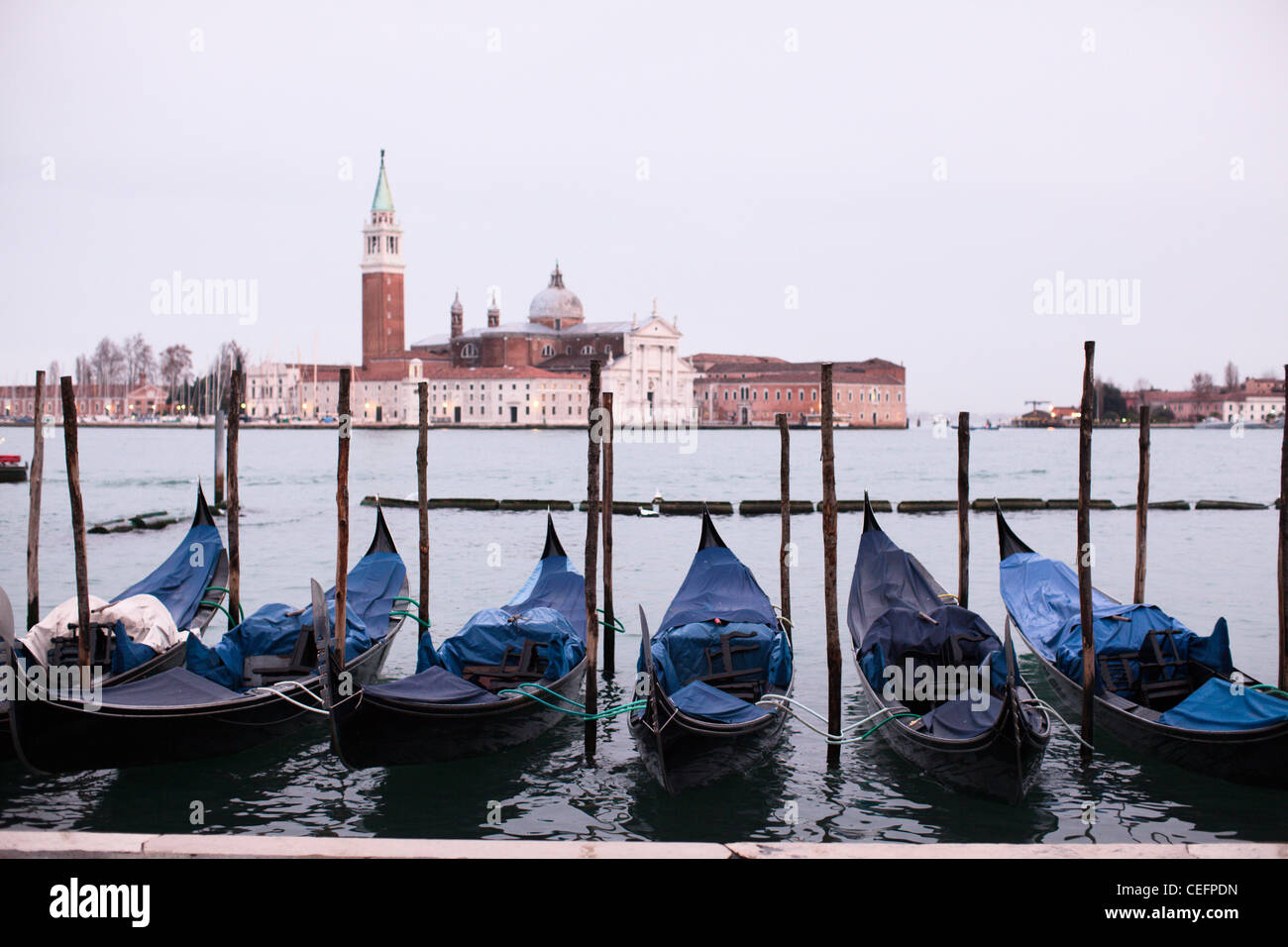 Gondolas moored up with the church of San Marco Maggiore in the distance. Venice, Italy. Stock Photo