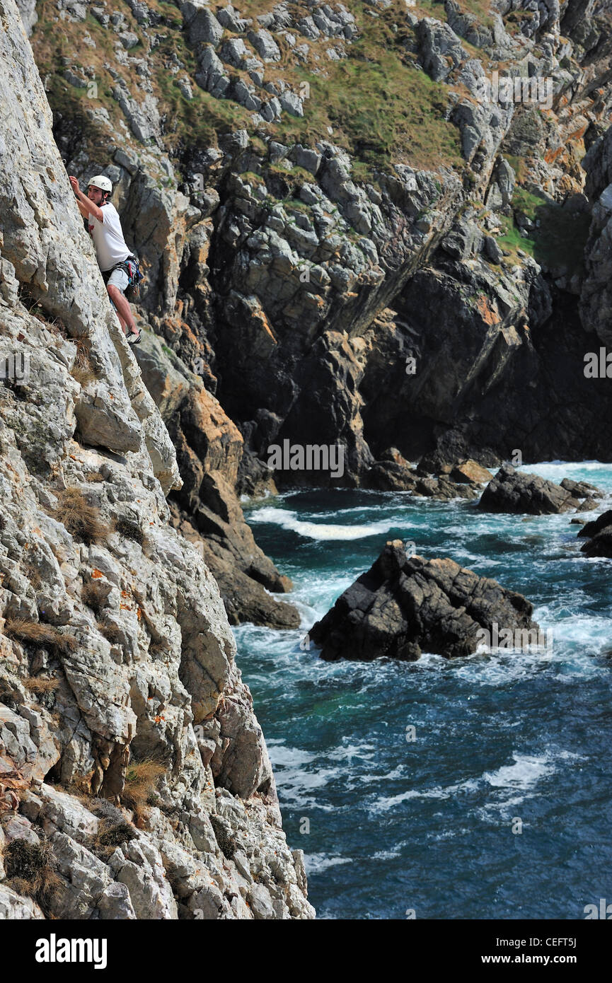 Rock climber climbing cliff face at the pointe de Pen-Hir, Finistère, Brittany, France Stock Photo