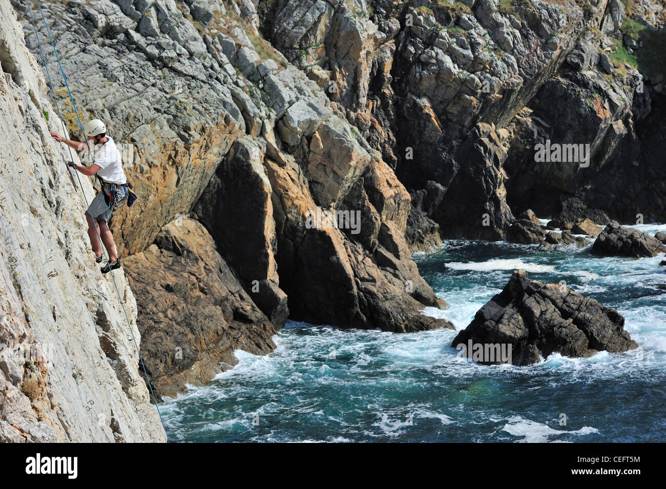 Rock climber climbing cliff face at the pointe de Pen-Hir, Finistère, Brittany, France Stock Photo