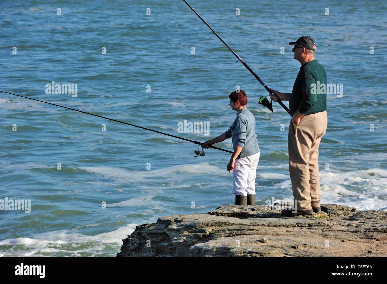 Couple of pensioner sea anglers fishing from cliff at the Pointe Saint-Gildas / Saint Gildas Point, Loire-Atlantique, France Stock Photo