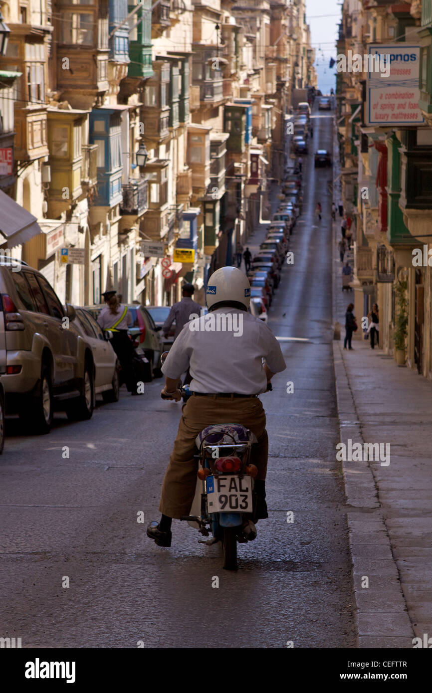 A man on a moped heads off down the lower level of St Ursula Street (Triq Sant' Orsla) in Valleta Stock Photo