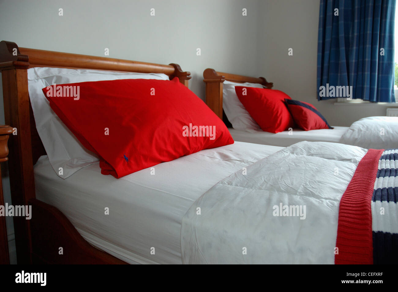 Red pillows on twin beds with white quilts in townhouse bedroom Stock Photo