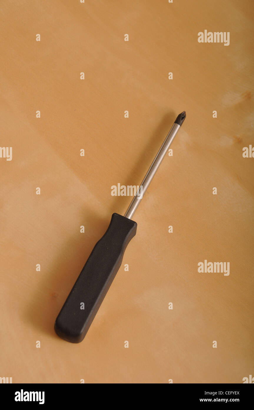 cross screwdriver with plastic handler on a brown wooden background ...
