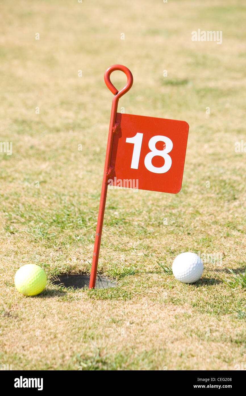 18th hole on a golf putting green with two golf balls. Stock Photo