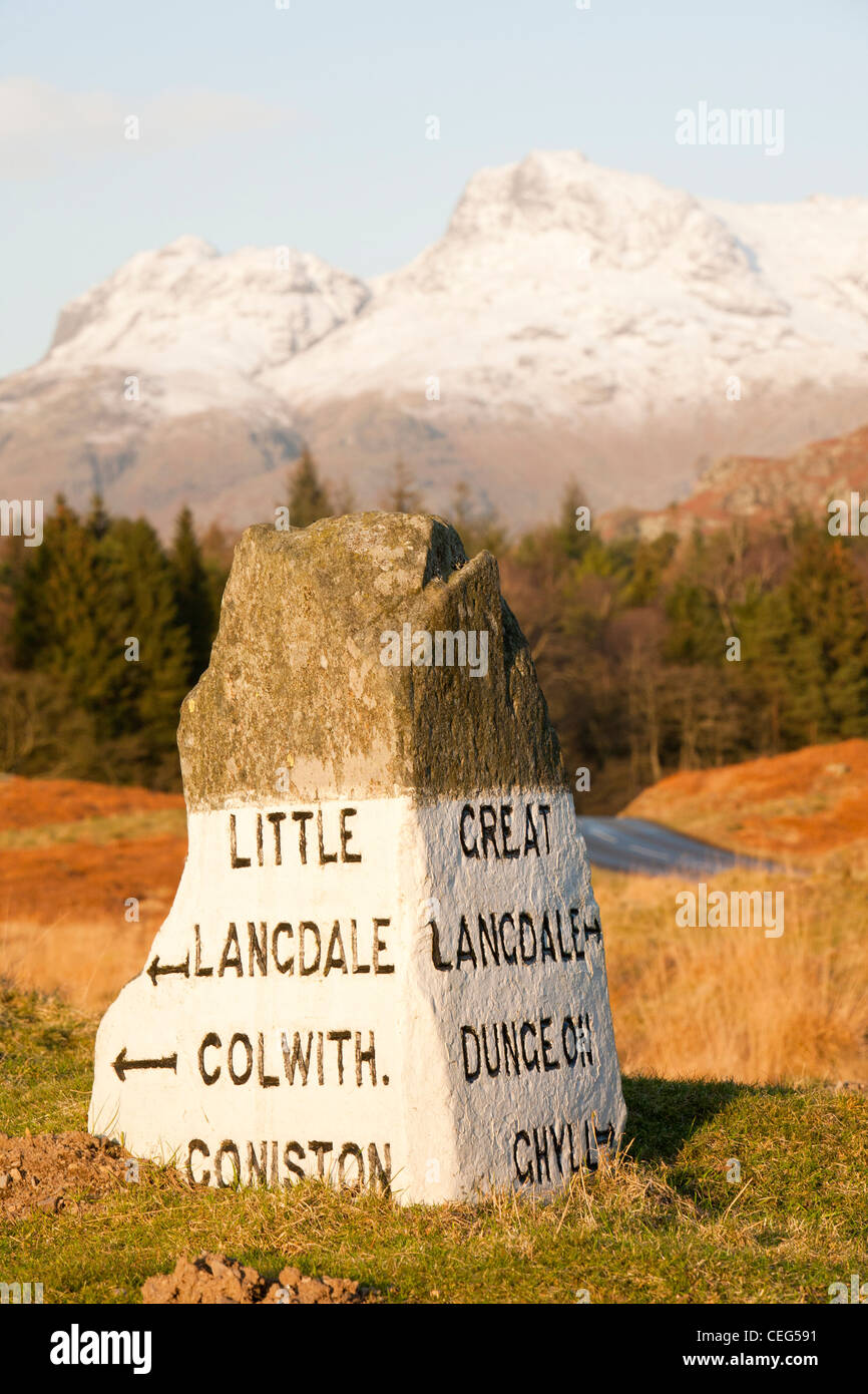 An old stone road sign in the Langdale valley at Elter water in the Lake District, UK, looking towards the Langdale Pikes. Stock Photo