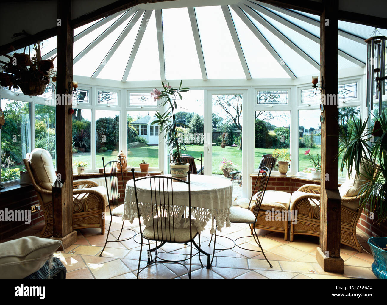 Metal chairs at table with white cloth in conservatory dining room with comfortable cane