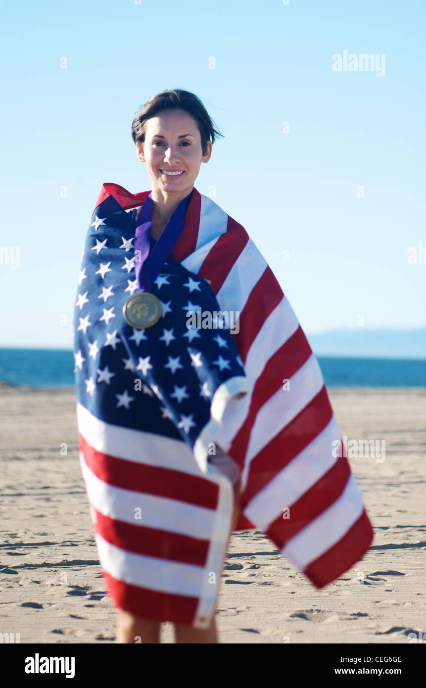 Portrait of a woman wrapped in an American flag wearing a simulated olympic gold medal. Stock Photo