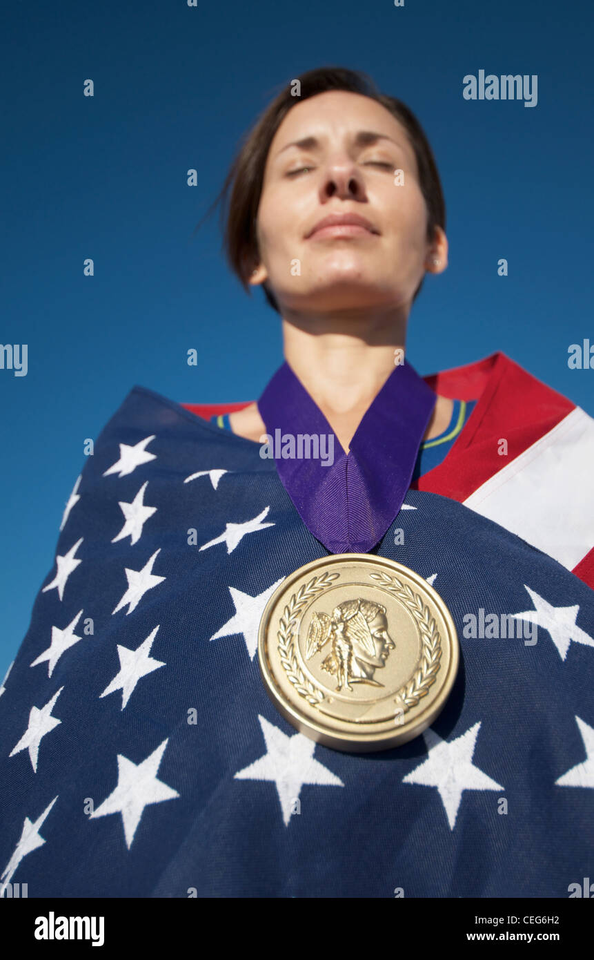 Portrait of a woman wrapped in an American flag wearing a simulated olympic gold medal. Stock Photo