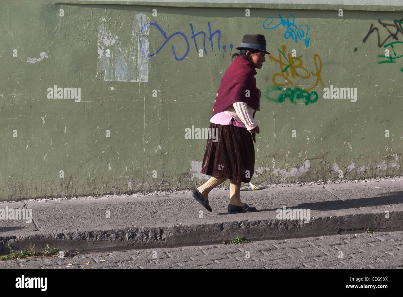 An Ecuadorian woman dressed in traditional indigenous clothing walks on a sidewalk in Latacunga, Ecuador. Stock Photo