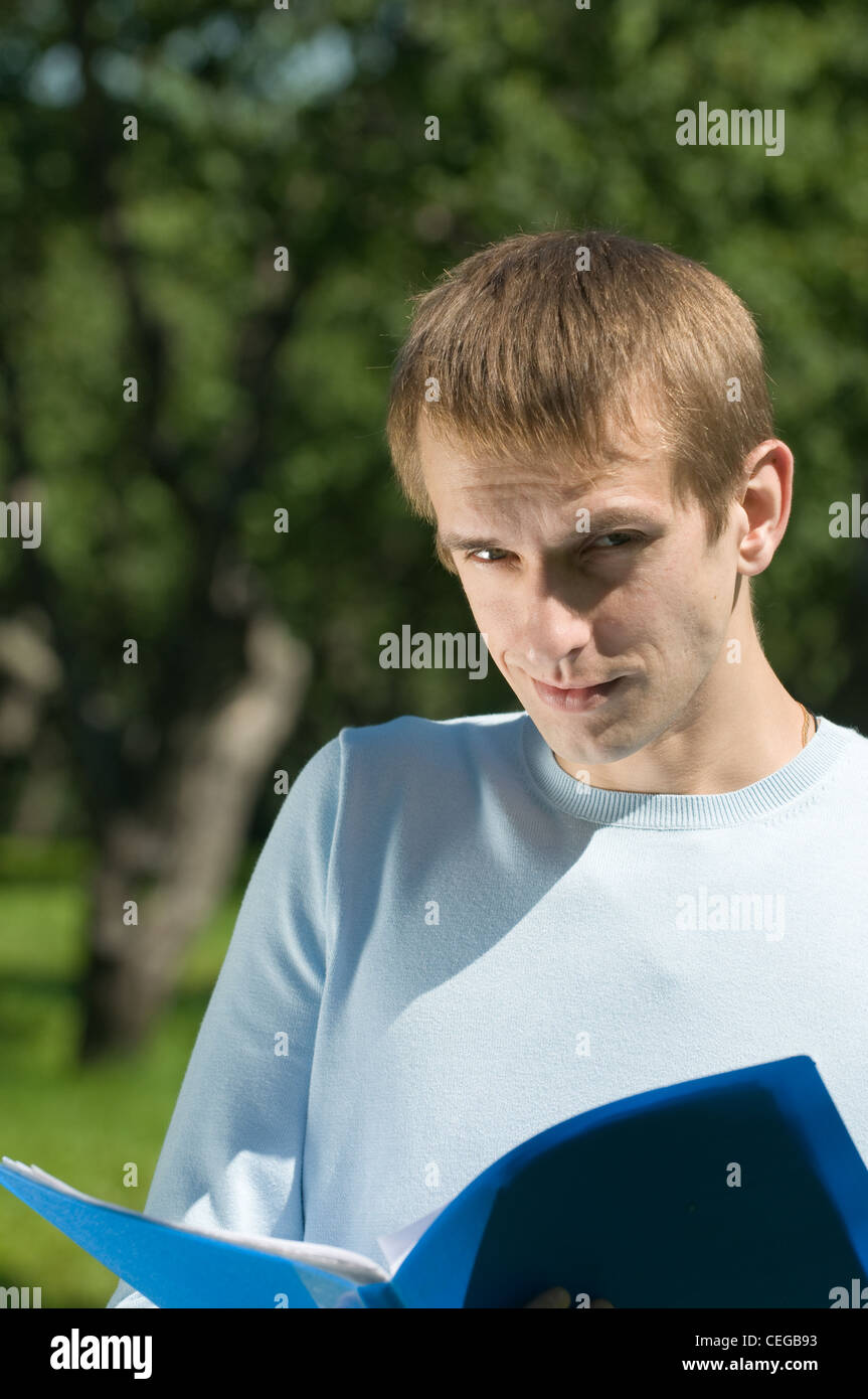 His Paper Young man studies his papers while in a green park Stock Photo - Alamy