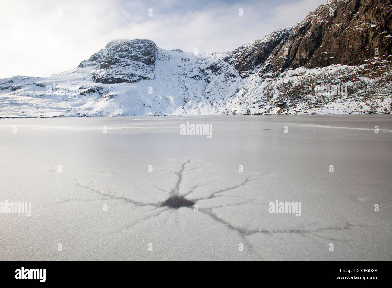 A frozen Stickle Tarn with crack patterns in the ice, above the Langdale valley in the Lake District, UK, Stock Photo