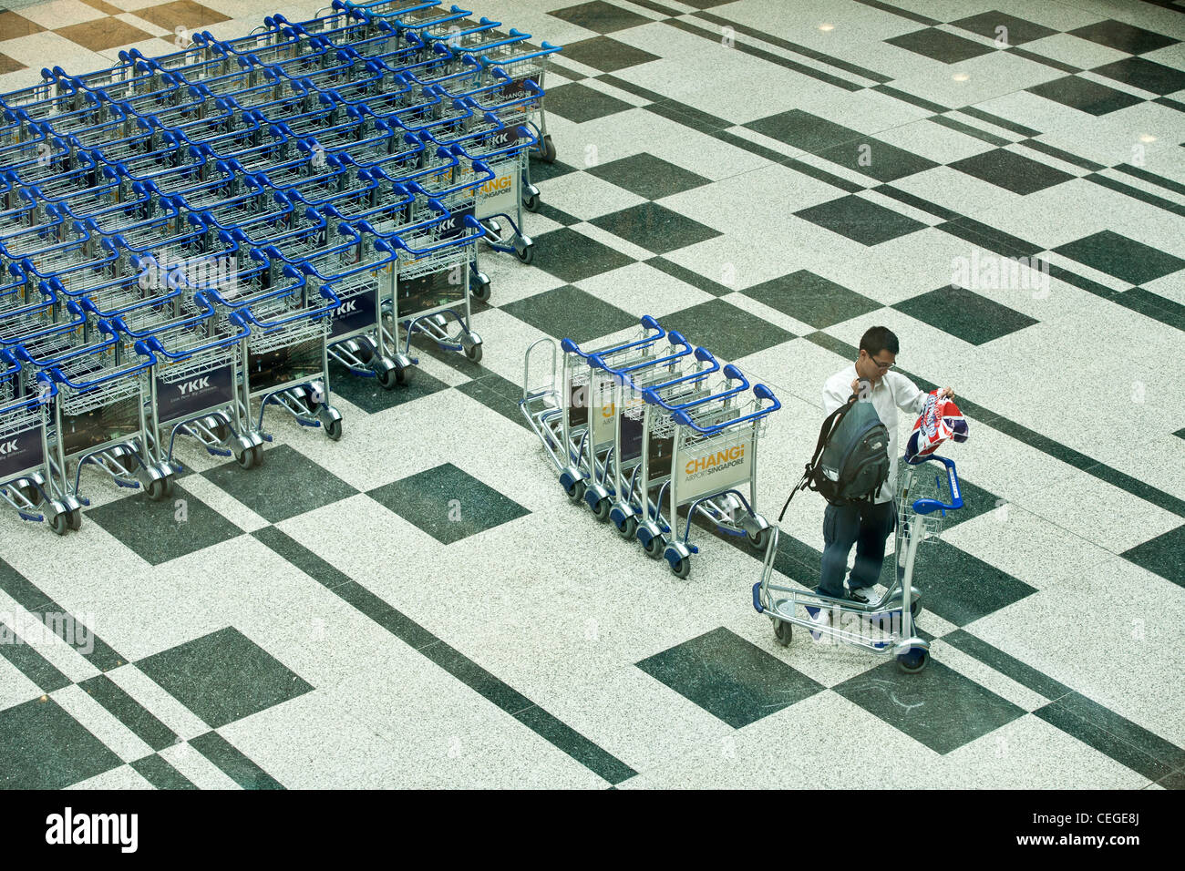 Passengers collect baggage trolleys in the arrivals area of Changi