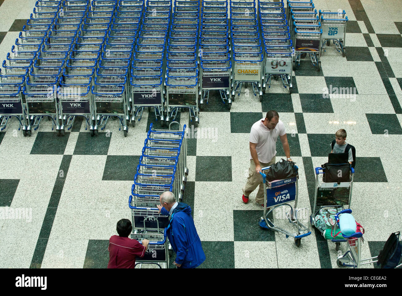 Passengers collect baggage trolleys in the arrivals area of Changi