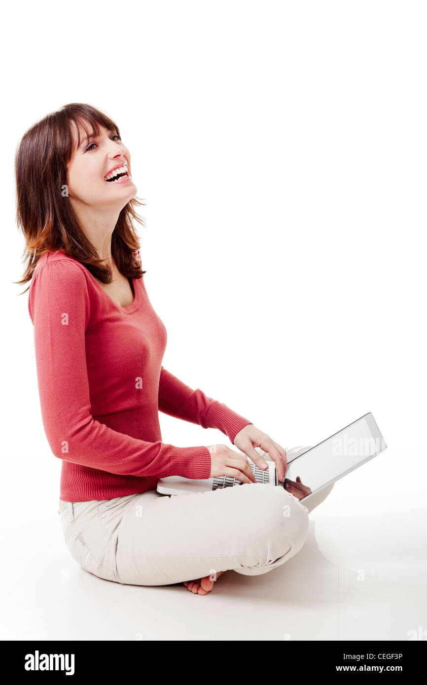 Beautiful woman sitting on the floor laughing and working with a laptop ...