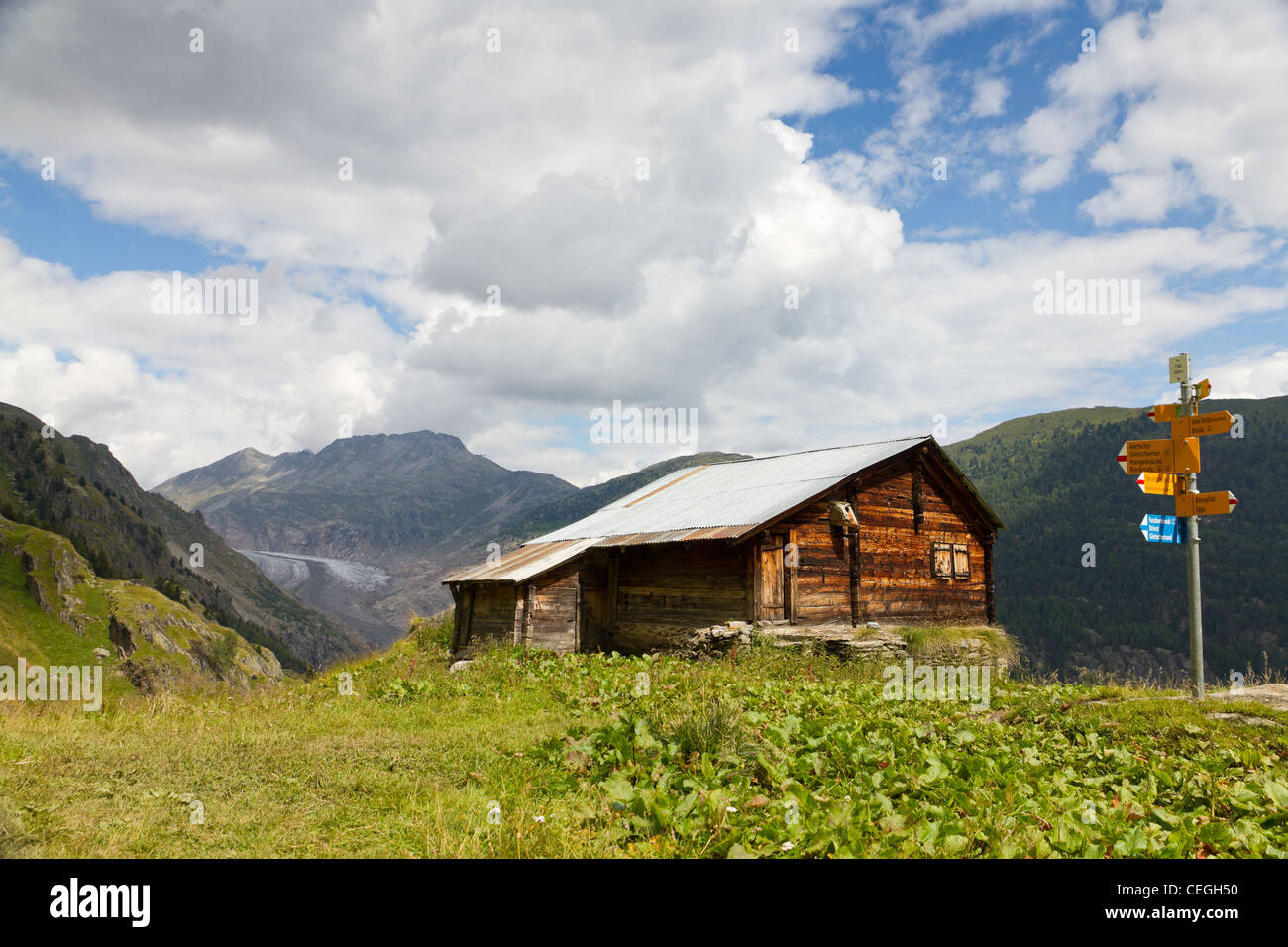 hiking outdoor sports - rustic timber hut with hiking signpost in front of Aletsch glacier valley, Switzerland Stock Photo