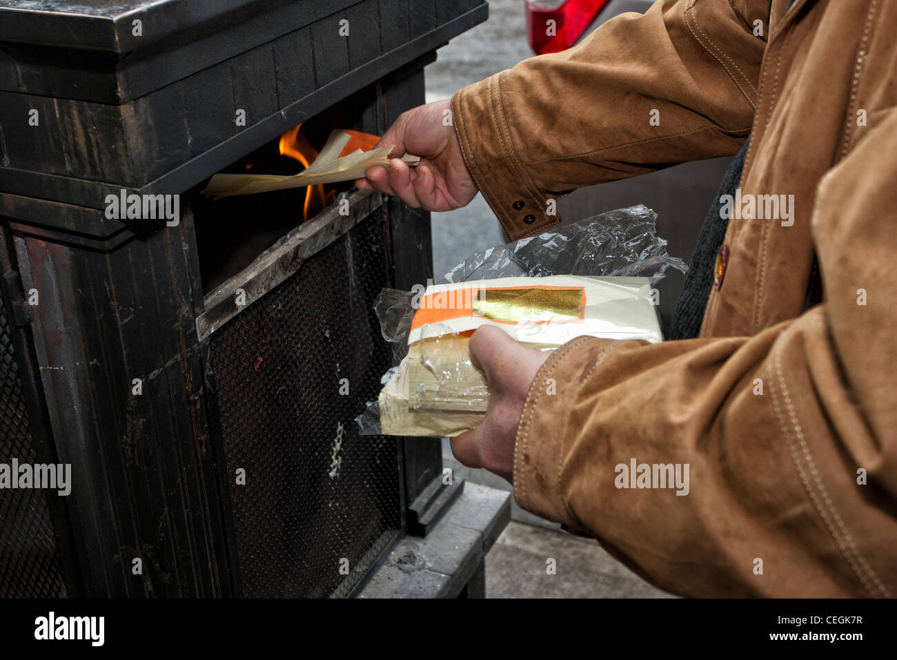 Chinese-American burning symbolic money for luck on the streets of New York City's Chinatown during 2012 Lunar New Year festival Stock Photo