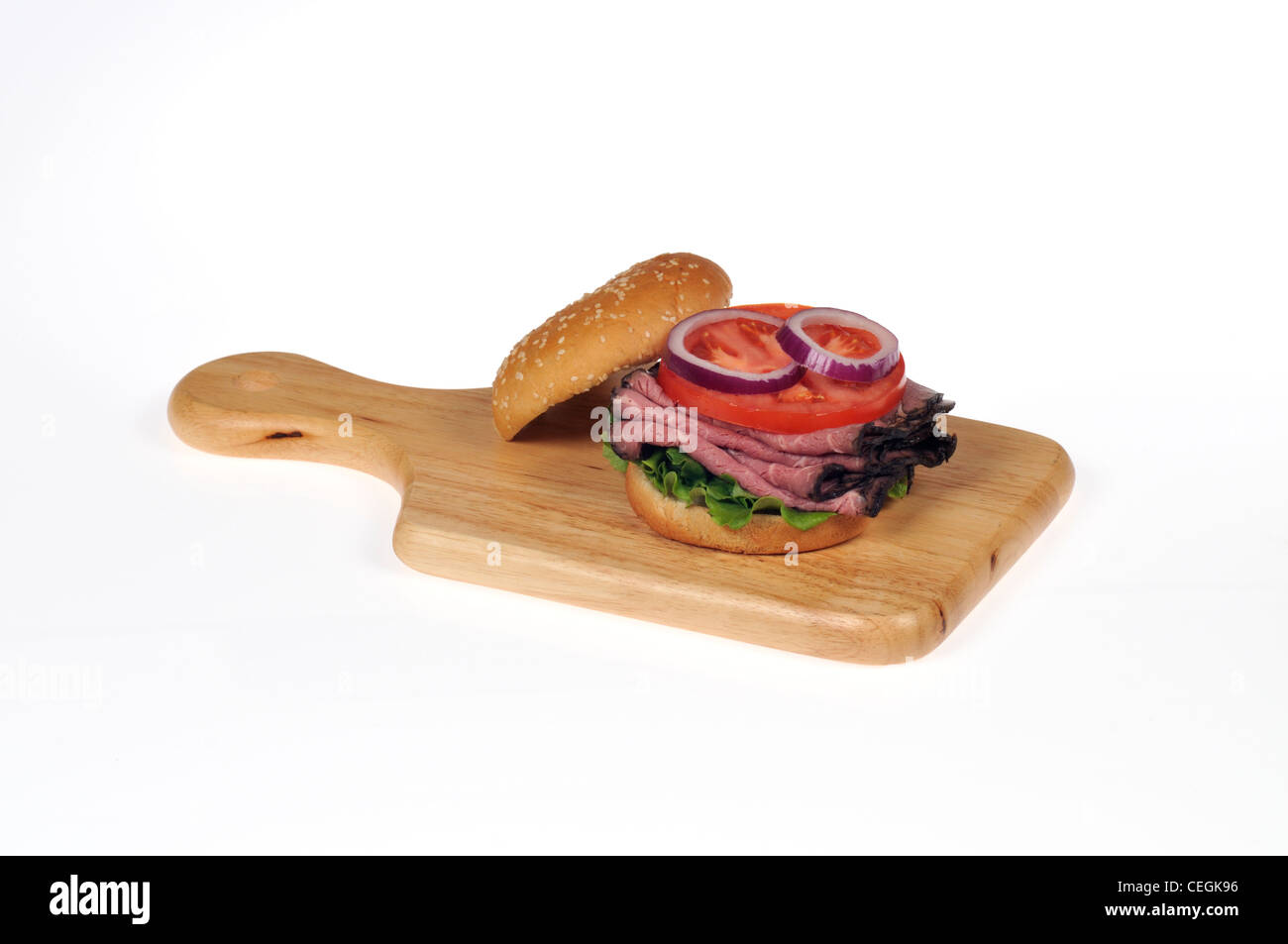 Roast beef with lettuce and tomato salad sandwich in bread 'sesame seed' roll on wood deli board on white background isolated Stock Photo