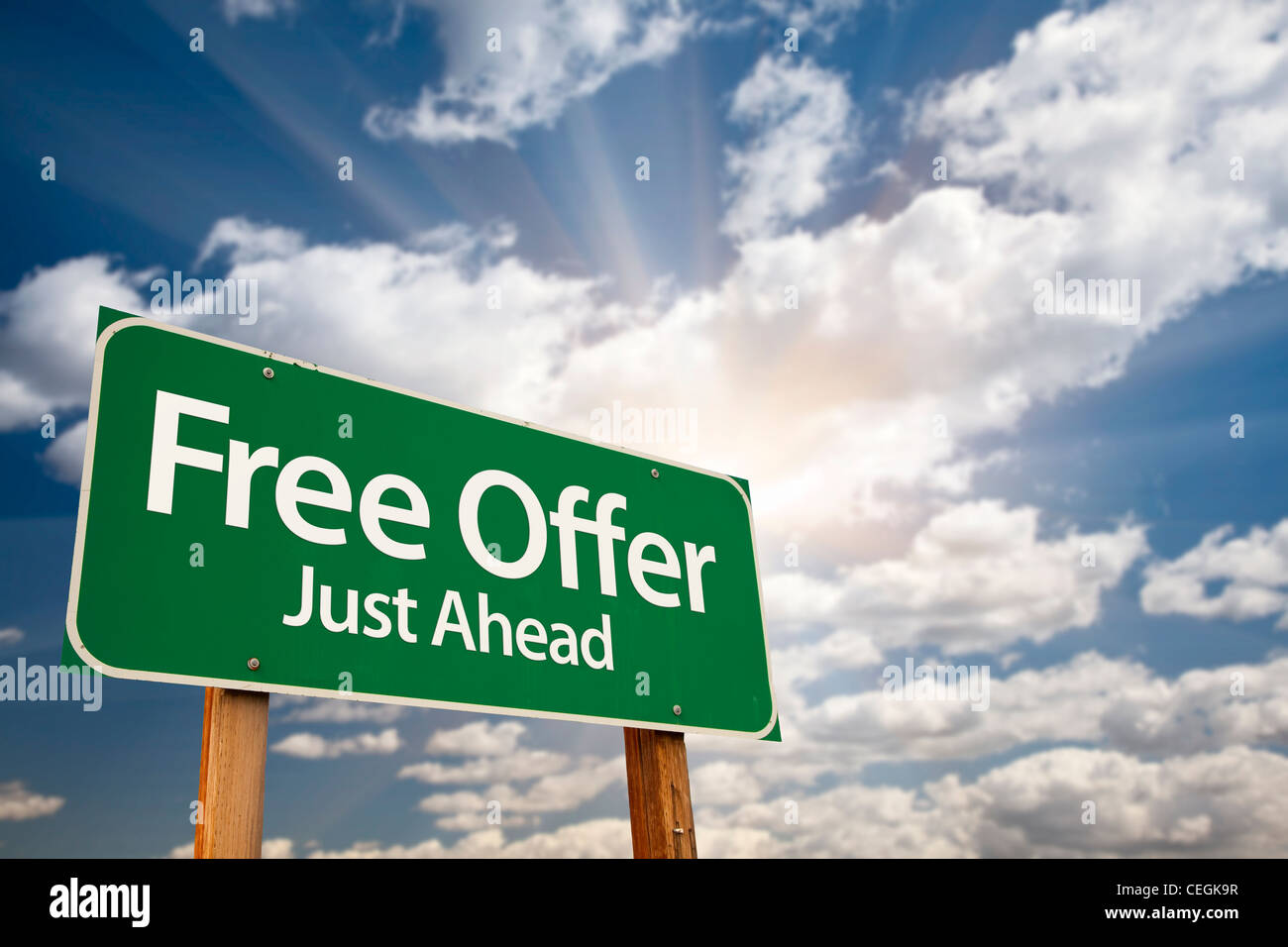 Free Offer Just Ahead Green Road Sign with Dramatic Clouds, Sun Rays and Sky. Stock Photo