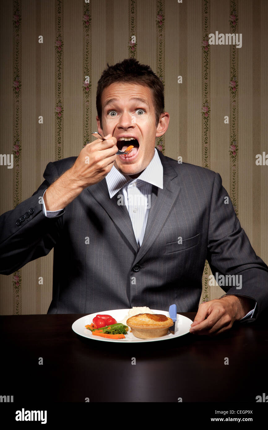 Man with a funny expression taking a bite Stock Photo