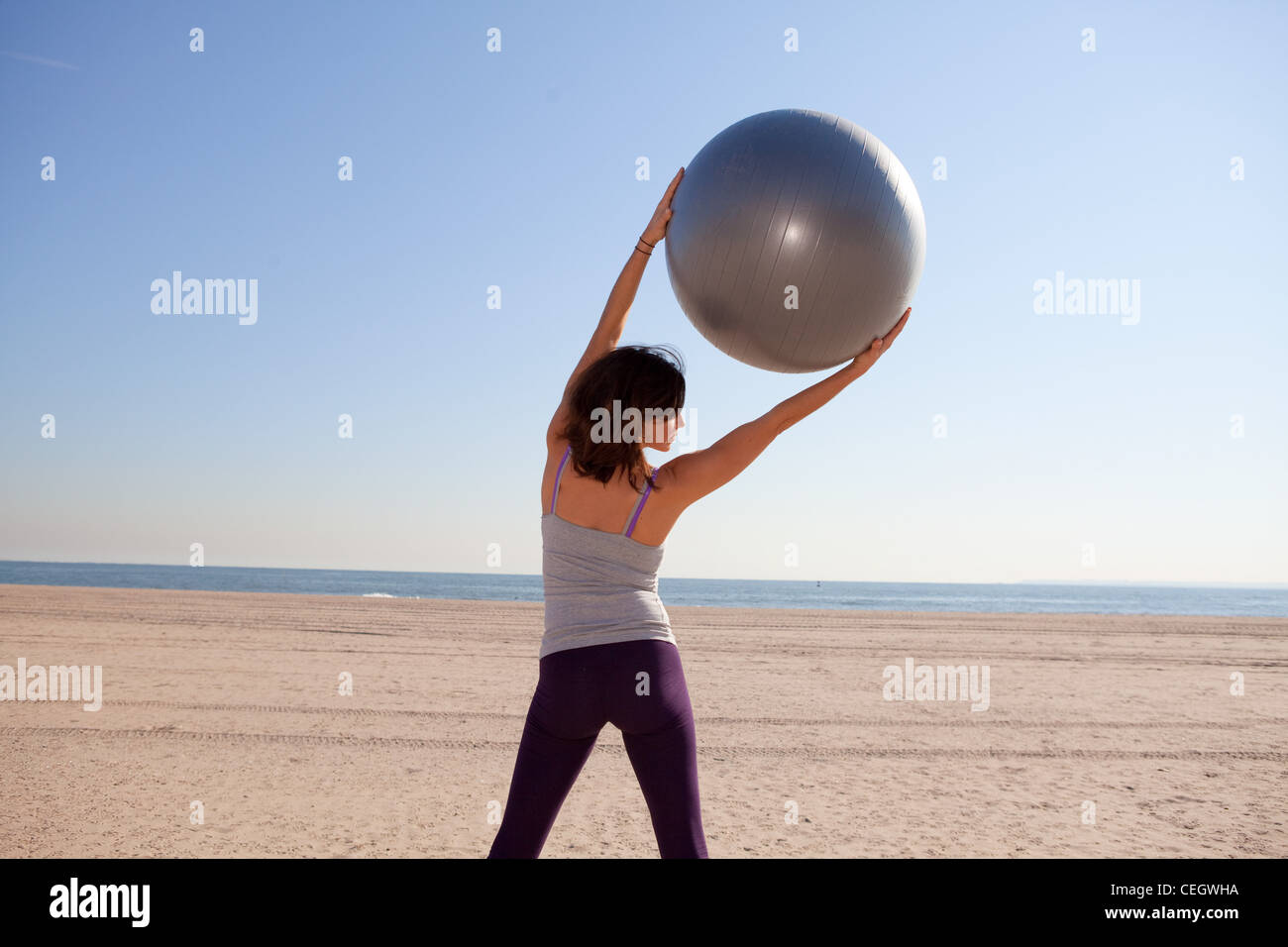 Woman on beach using exercise ball Stock Photo