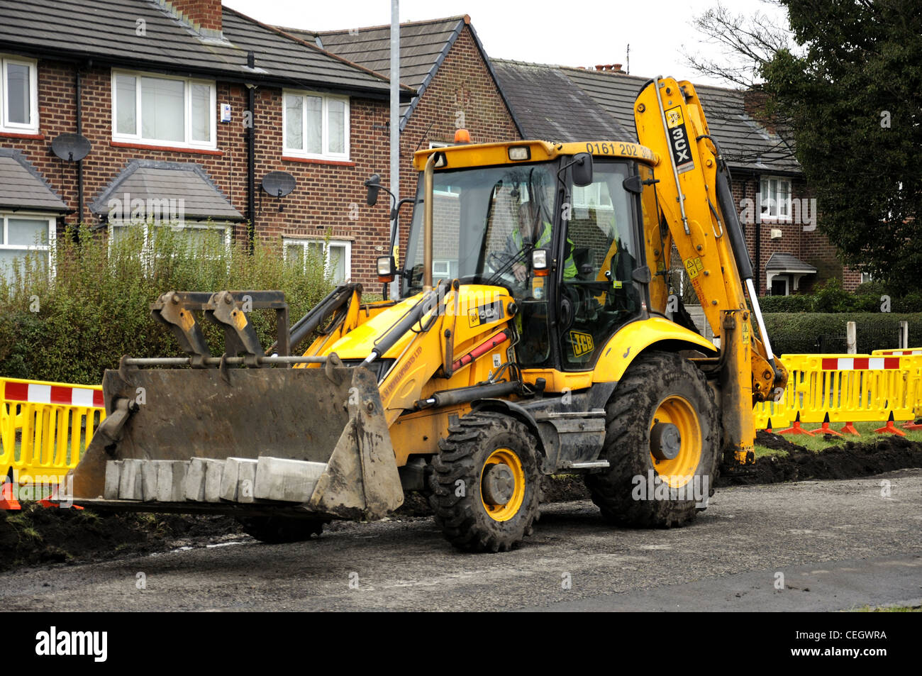 Yellow JCB and driver with kerb edgings in bucket Stock Photo