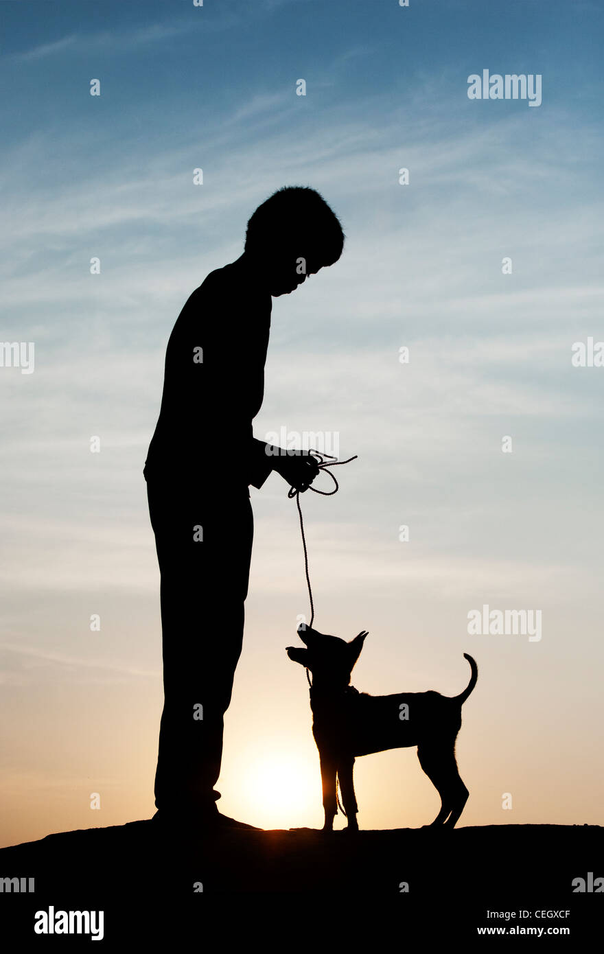 Silhouette of young Indian boy standing with his puppy. India Stock Photo