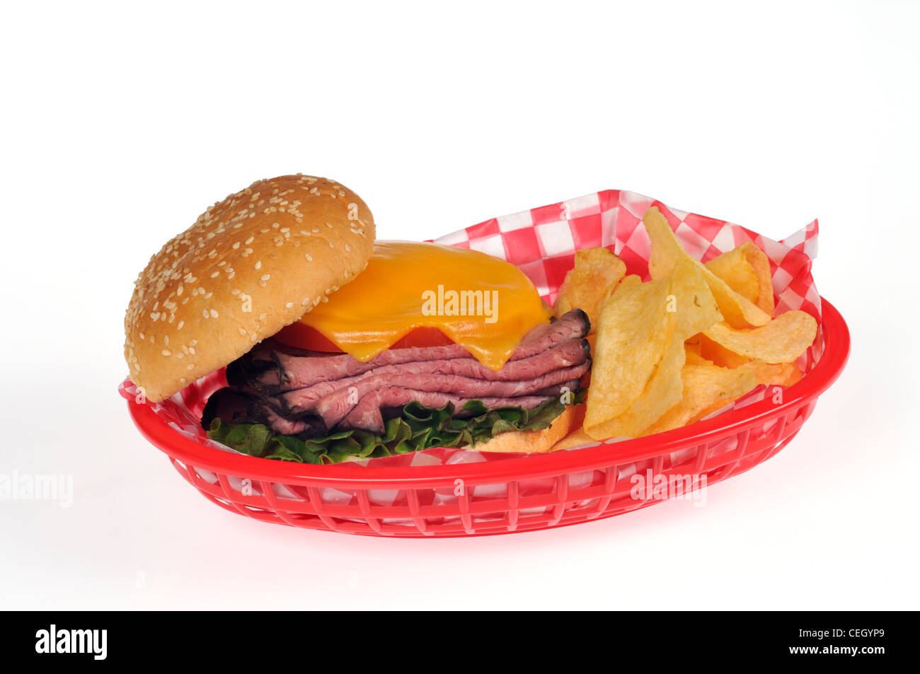 Sandwich with roast beef, lettuce, tomato salad and melted cheese on sesame seed bread roll in red retro basket with potato chips or crisps on white Stock Photo