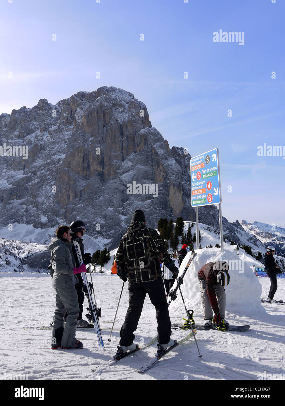 Skiers and snowboarders looking at the piste notice board on the Sellaronda ski circuit in Italy Stock Photo