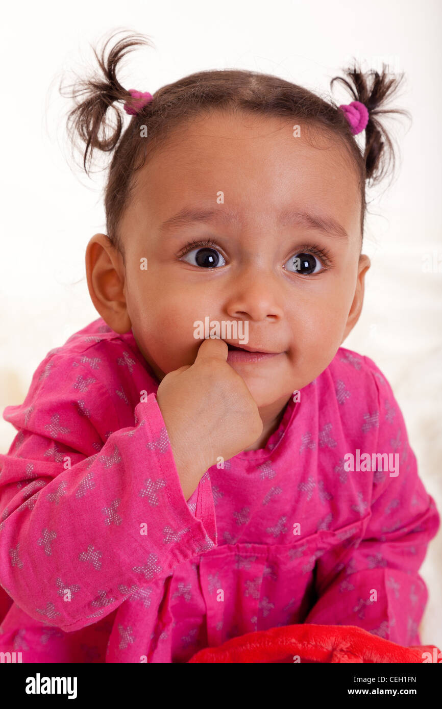 Beautiful mixed race baby girl with his finger in the mouth Stock Photo