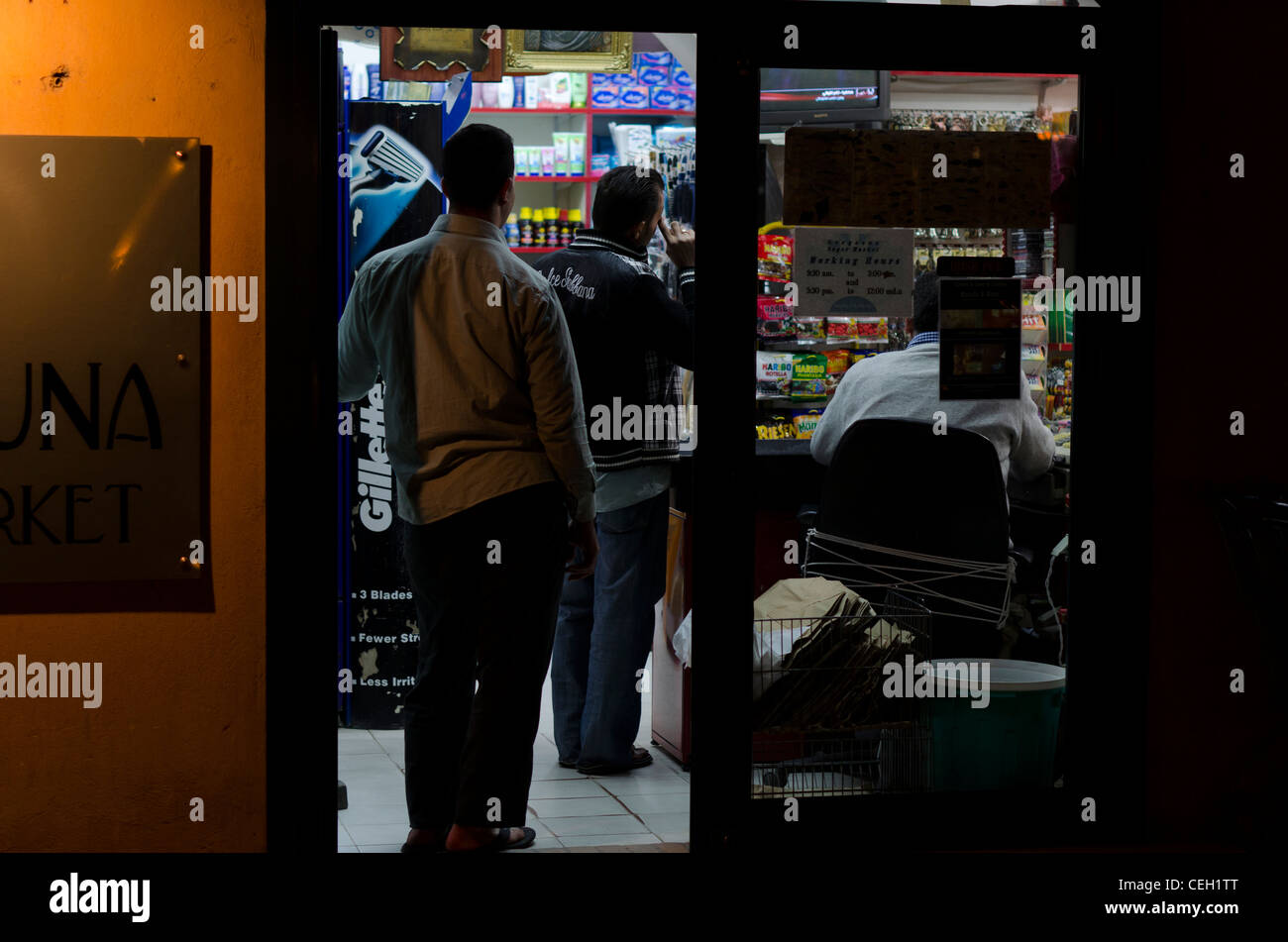 People in minimarket watching tv late at night Stock Photo