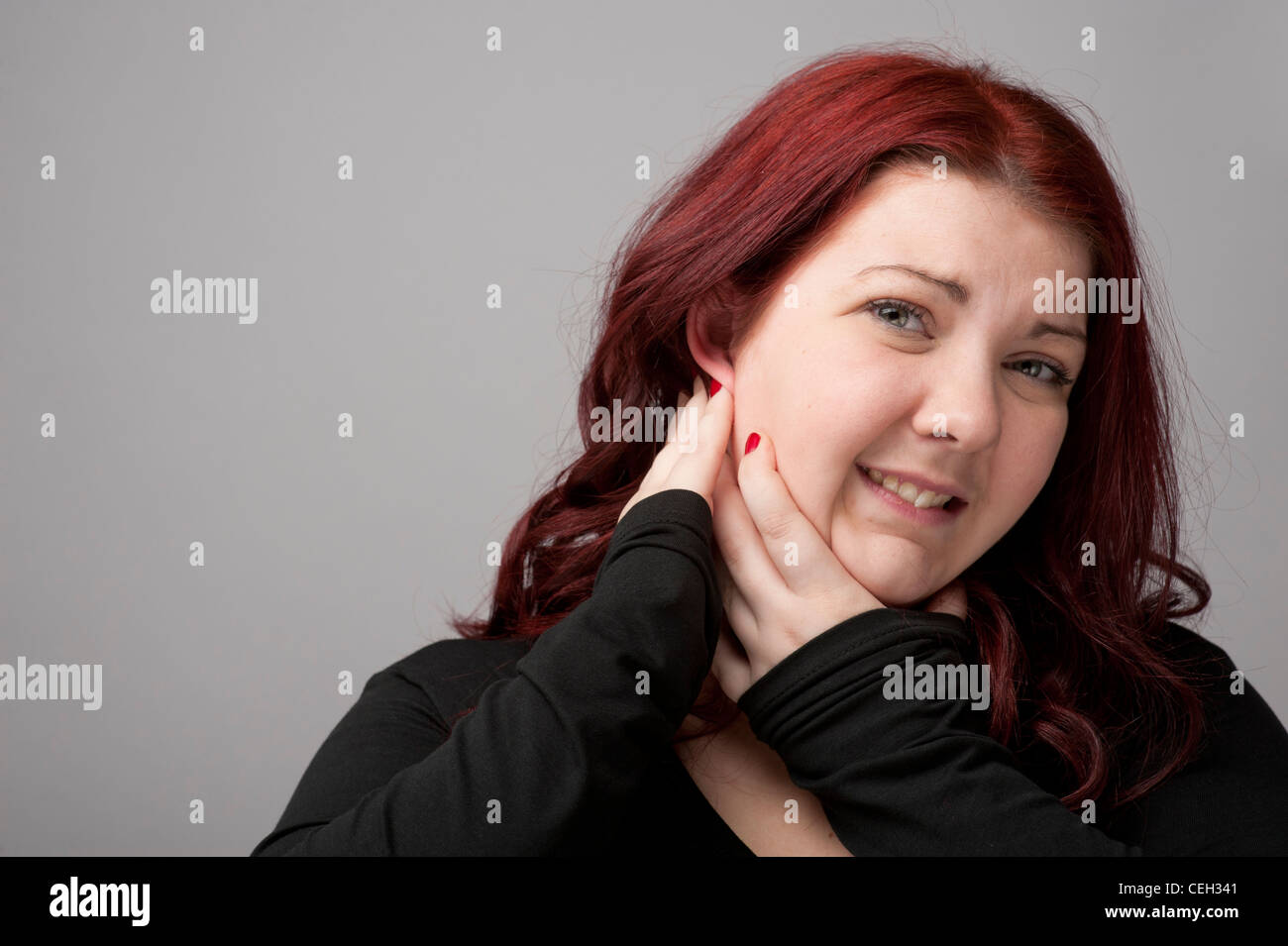 A auburn haired caucasian woman suffering from earache pain in the ear Stock Photo