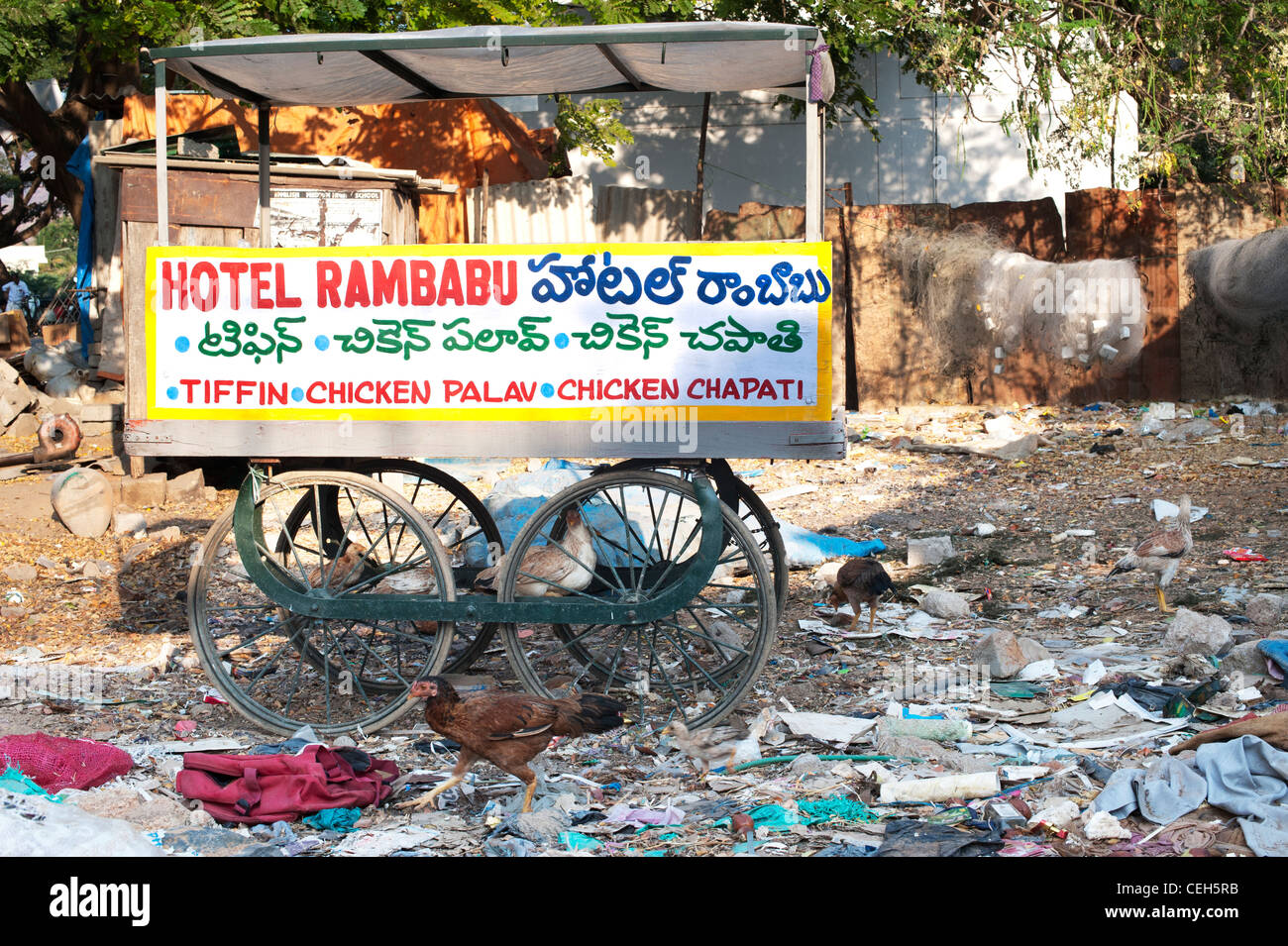 Indian food cart in the middle of a rubbish tip surround by chickens. Andhra Pradesh, India Stock Photo