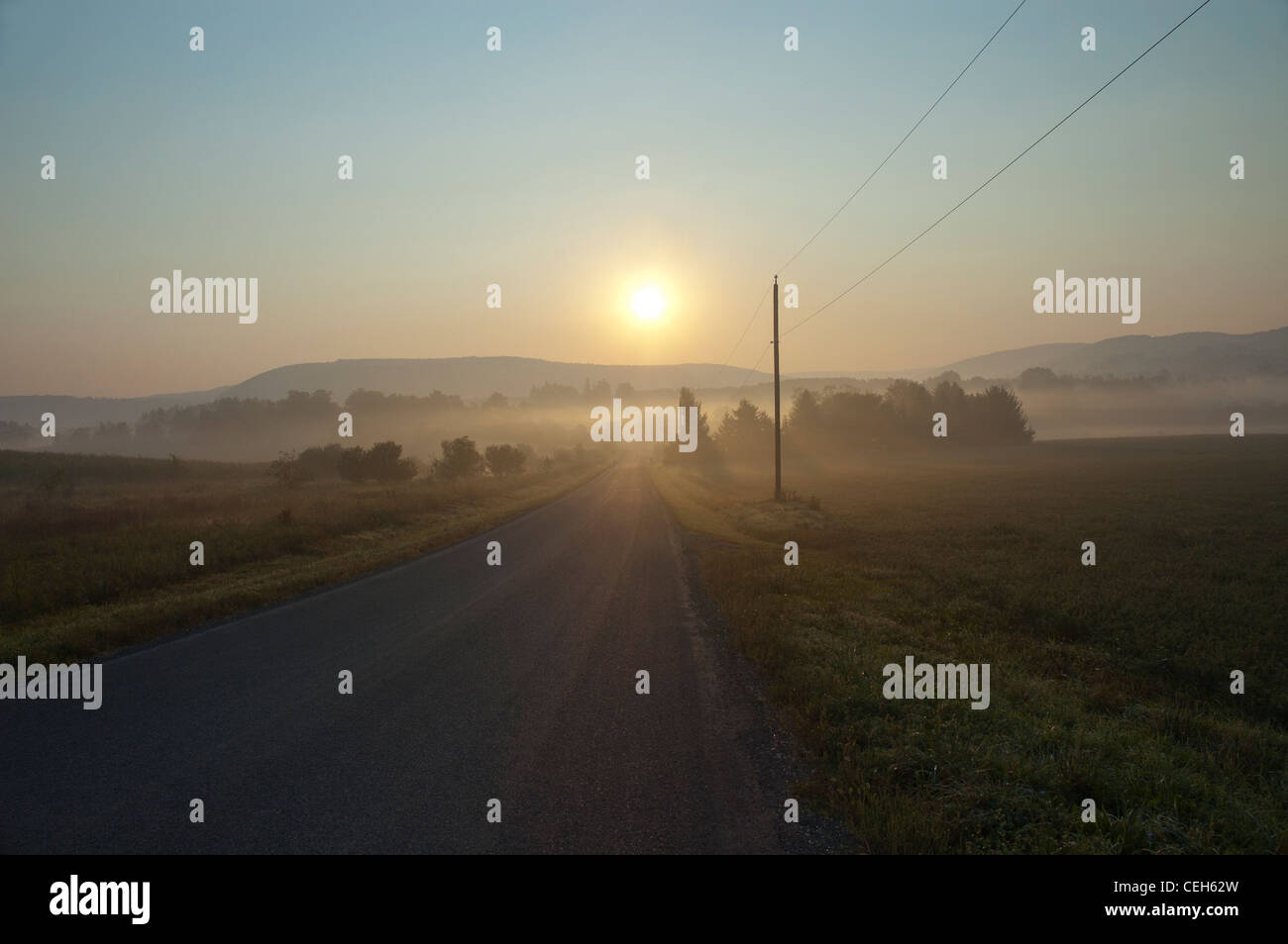 sunrise over empty road with fog or mist Stock Photo - Alamy