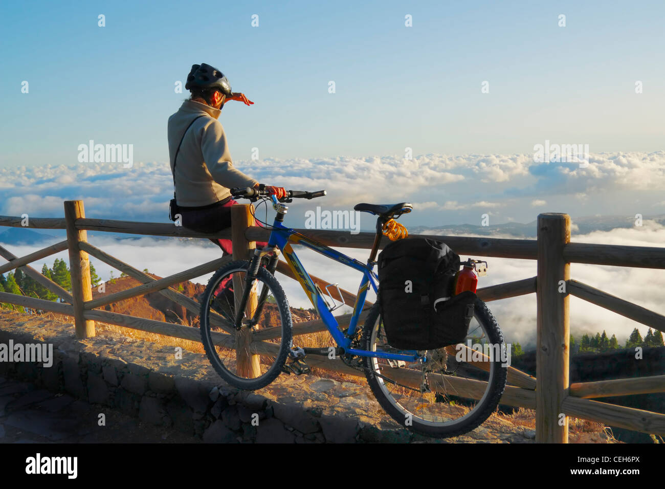 Woman with Mountain Bike above cloud layer at sunset at Pinos de Galdar on Gran Canaria, Canary Islands, Spain Stock Photo