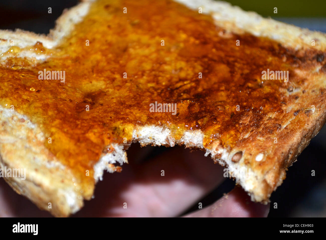 A piece of toast with honey with a bite taken out of it Stock Photo
