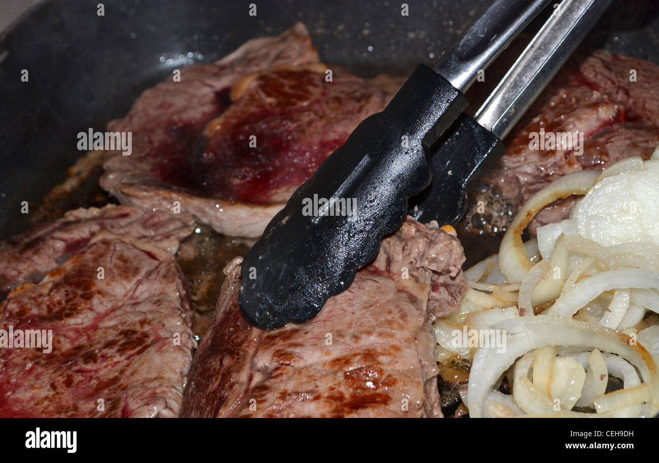 Steak and onions cooking in a fry pan Stock Photo Alamy