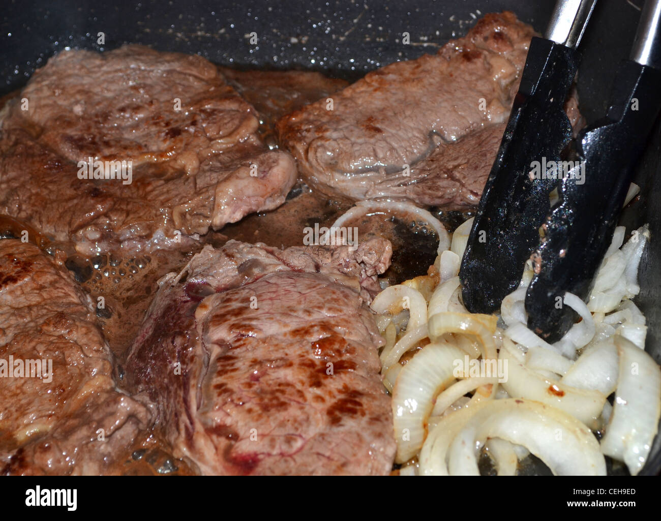 Steak and onions cooking in a fry pan Stock Photo Alamy