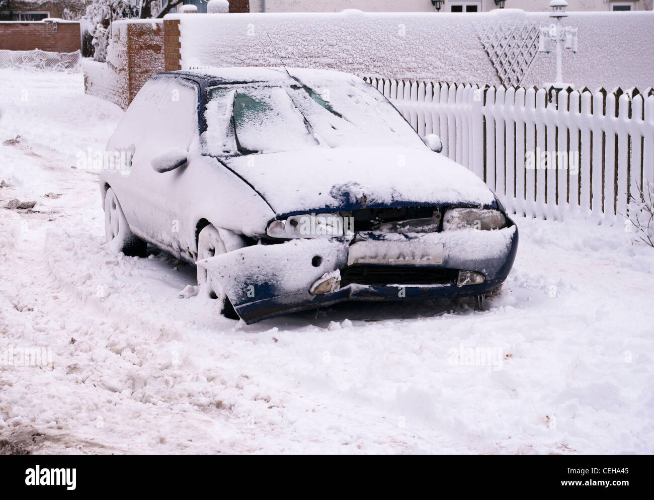 Damaged Dented Broken Down Car Vehicle After an Accident In The Snow Winter UK Stock Photo
