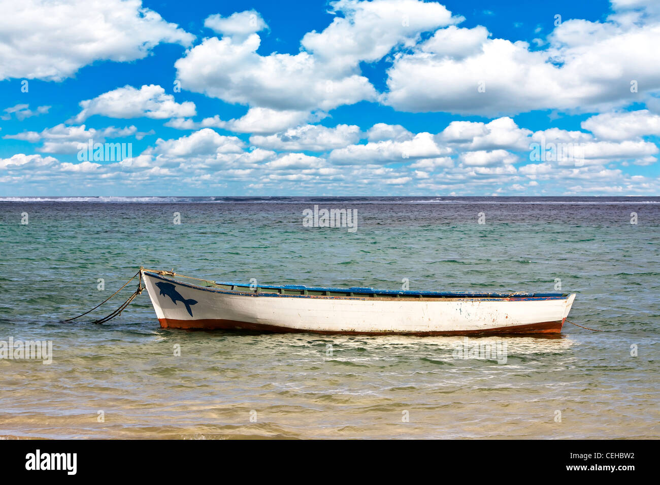 Old boat anchored on tropical island with beautiful summer clouds Stock Photo