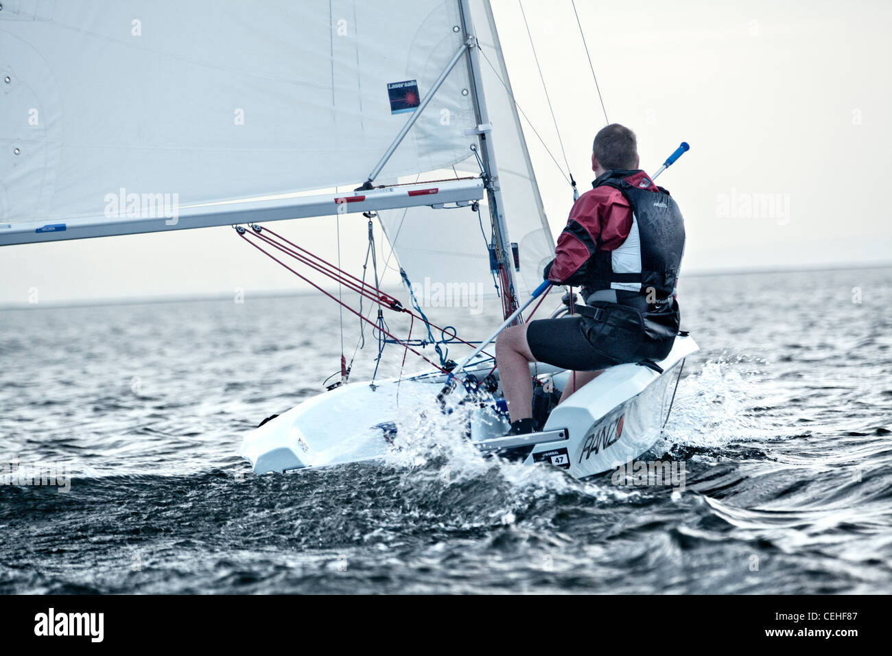 a man sailing in a dinghy towards the horizon with the water wake