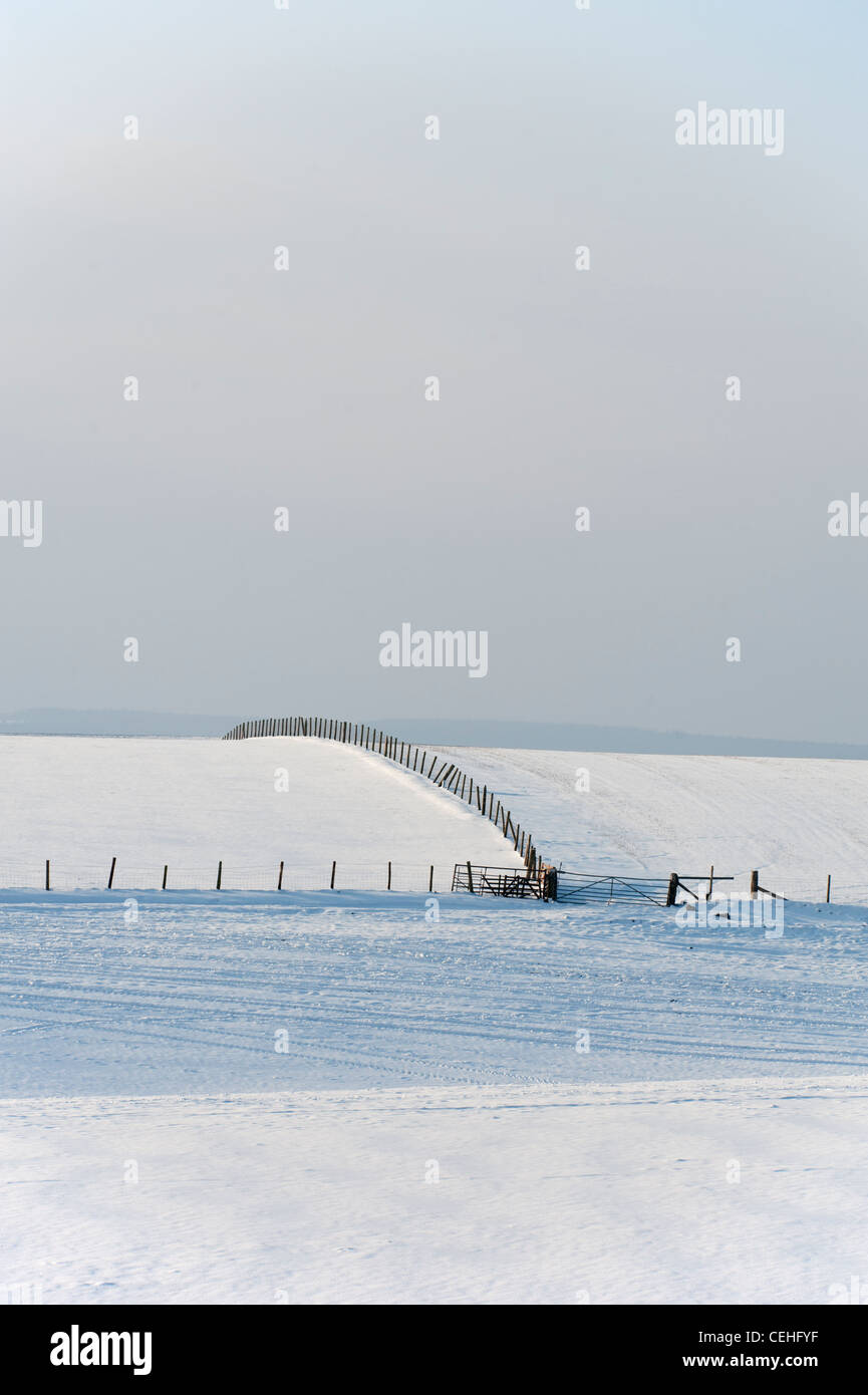 Snow covered fields under cloudy sky Stock Photo