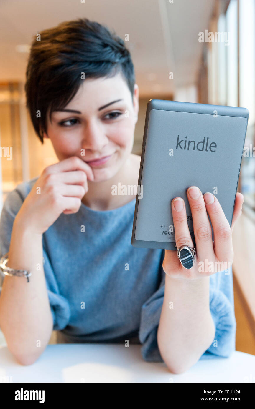 Young woman reading ebook on an Amazon Kindle, London, England, UK Stock Photo