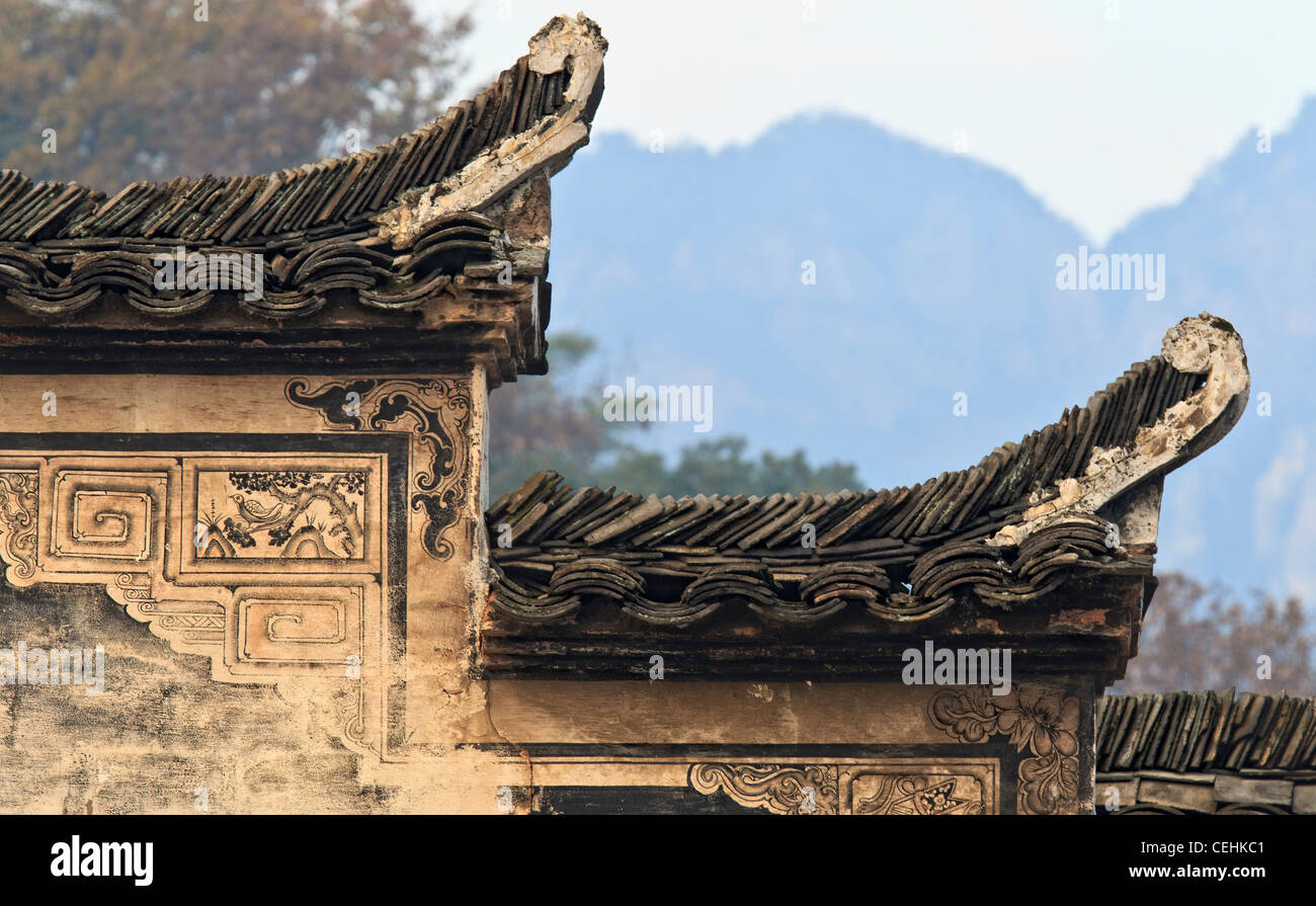 A Chinese Hui Style house with black roof tiles, white wall, and decorated with artworks. Mountains in the background Stock Photo